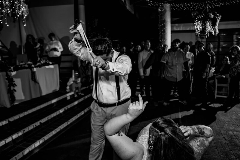 Groom holding up the garter after the search, flexing for the crowd before the toss