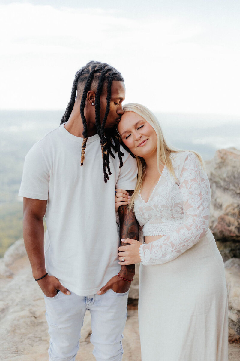 man kissing woman's head