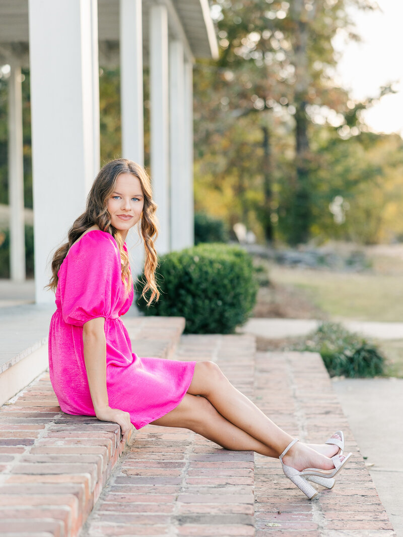 girl in a hot pink dress sitting on steps