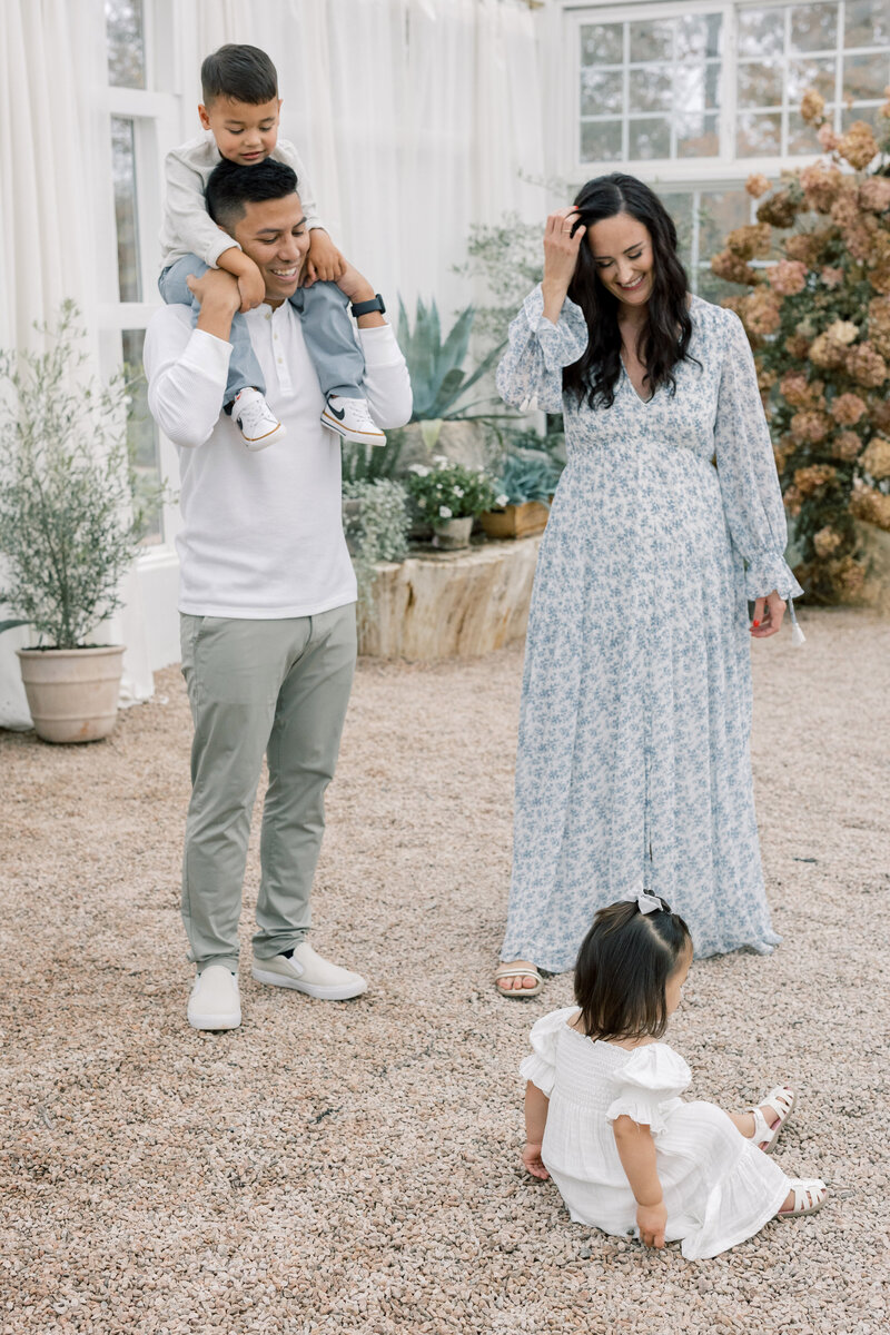 Family of four walking hand in hand outdoors in coordinating soft blue and gray outfits.