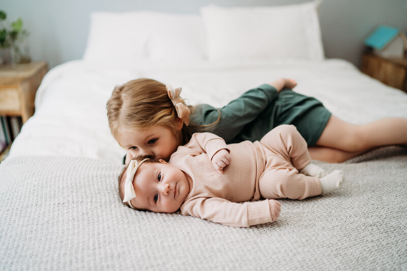 girl kissing her baby sister in boston newborn session
