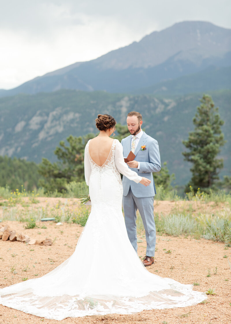 Theresa and Brian in front of blue mountains while they say their vows. Ceremony in Woodland Park, Colorado.