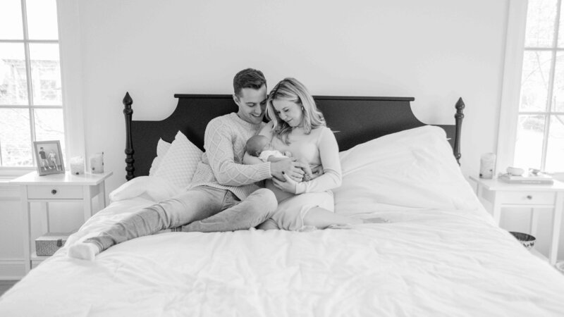 Chicago newborn photographer captures an image of a couple on their bed snuggling their newborn son