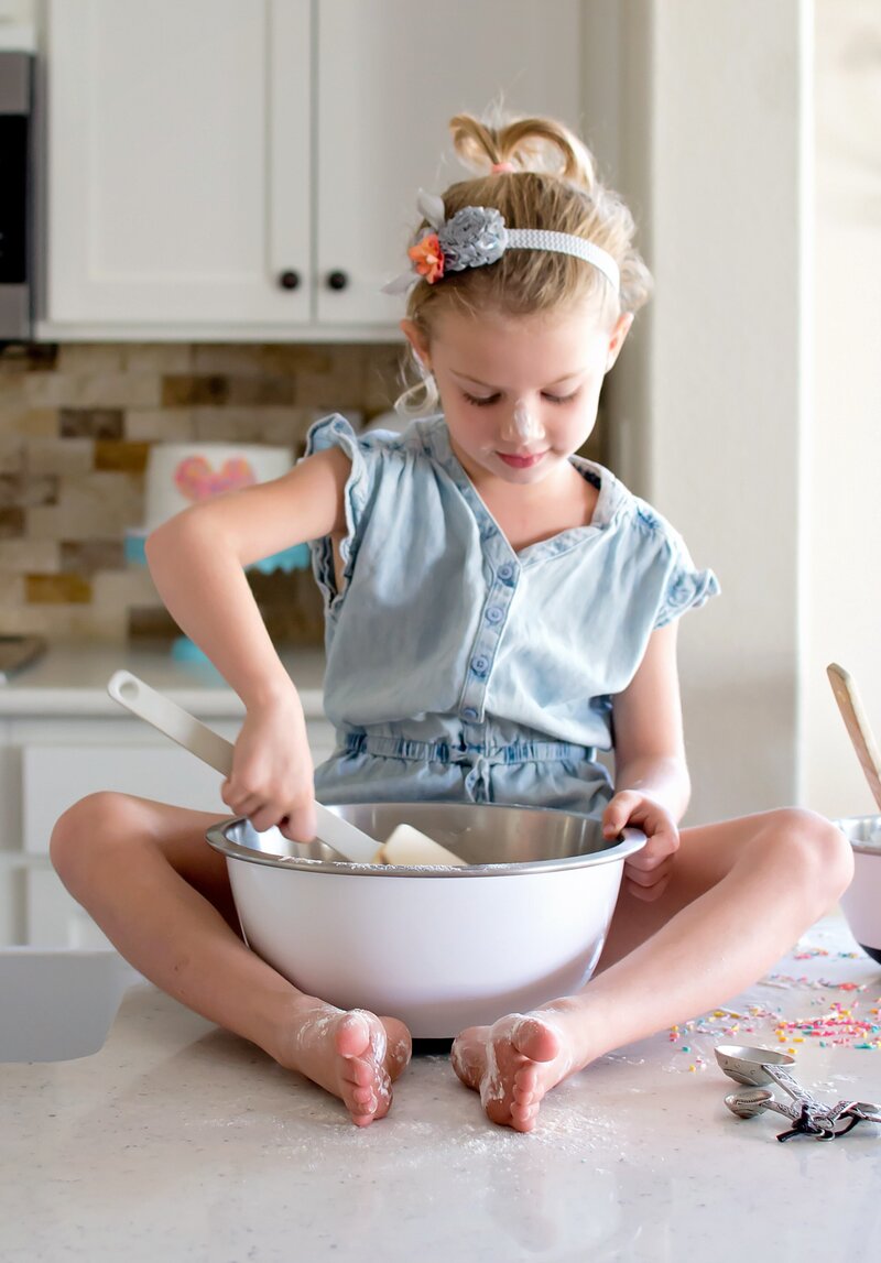 Lifestyle Photography. Little girl mixing the cake batter on the counter.