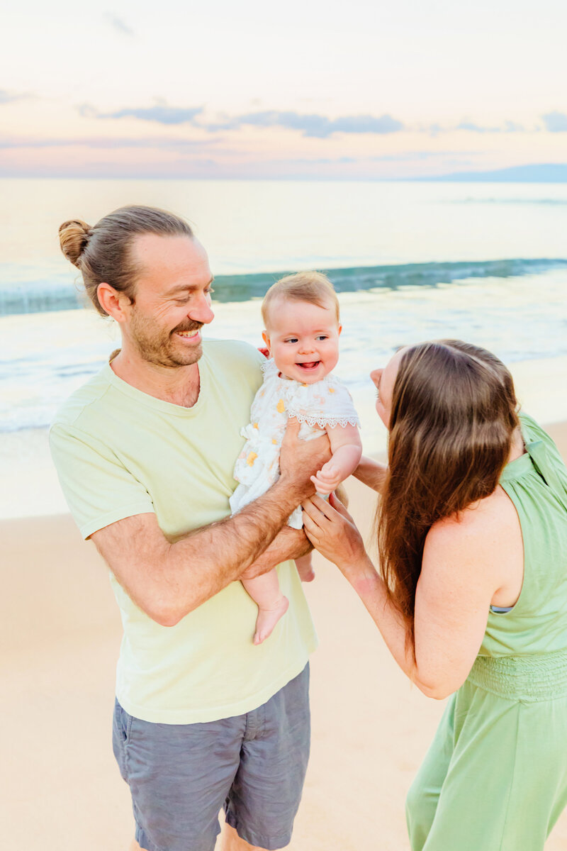 mom of young baby tickles while dad smiles and laughs with love and water photoshoot