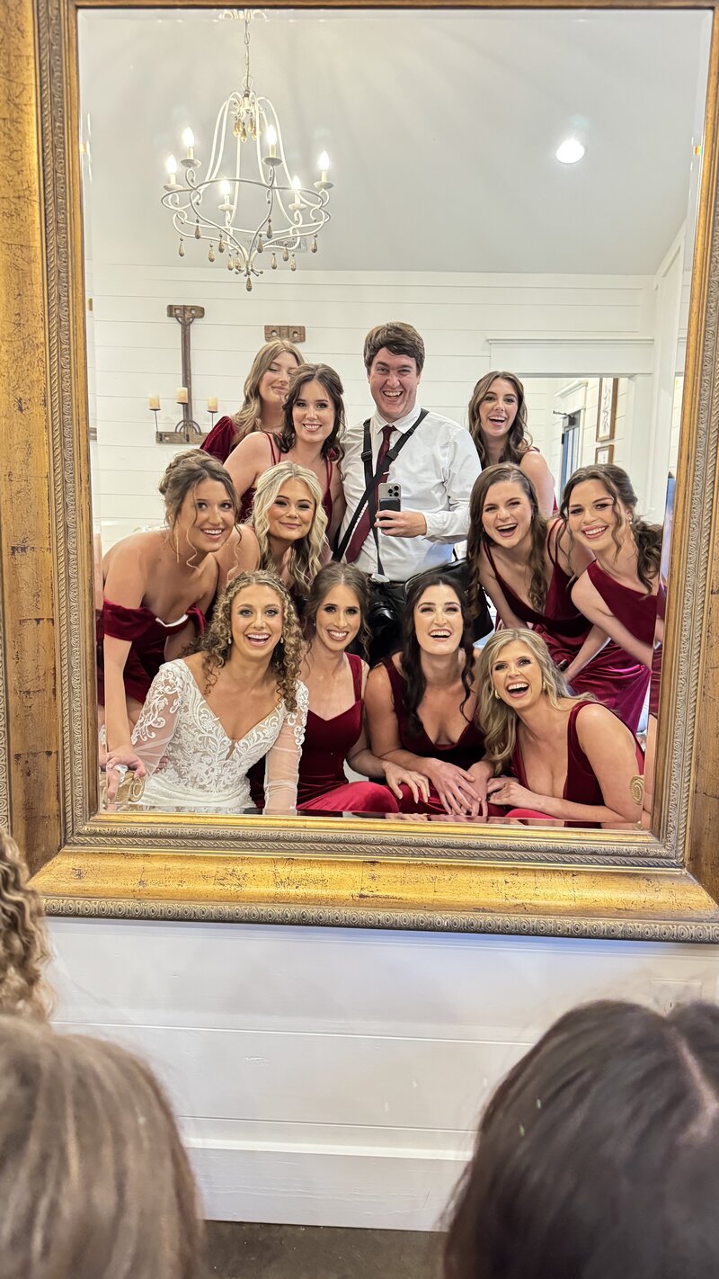 A group photo on a wedding day with the wedding photographer in the center surrounded by the bride and  bridesmaids.