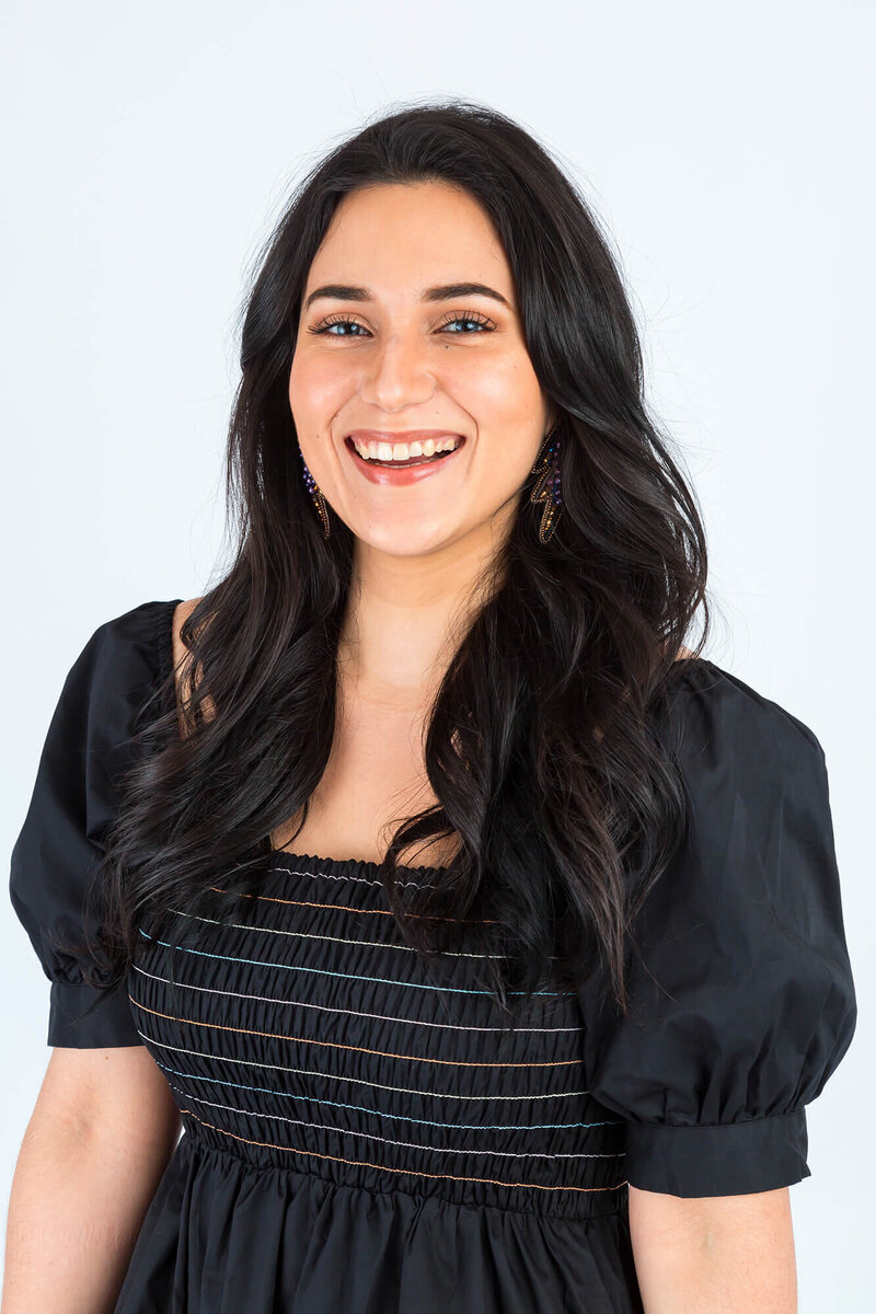 Woman in black puff sleeved dress on white backdrop