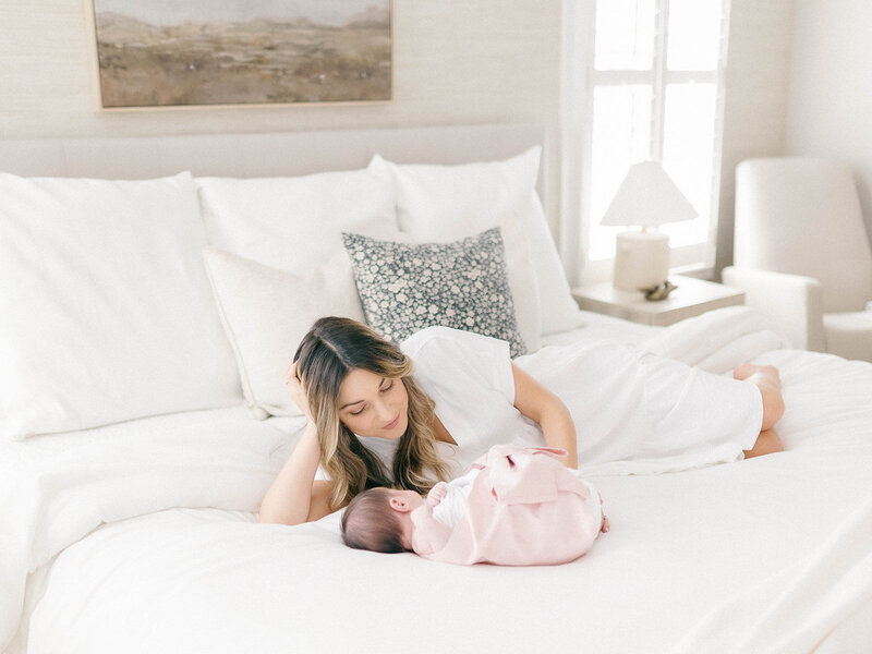 mom and newborn baby girl laying in bed