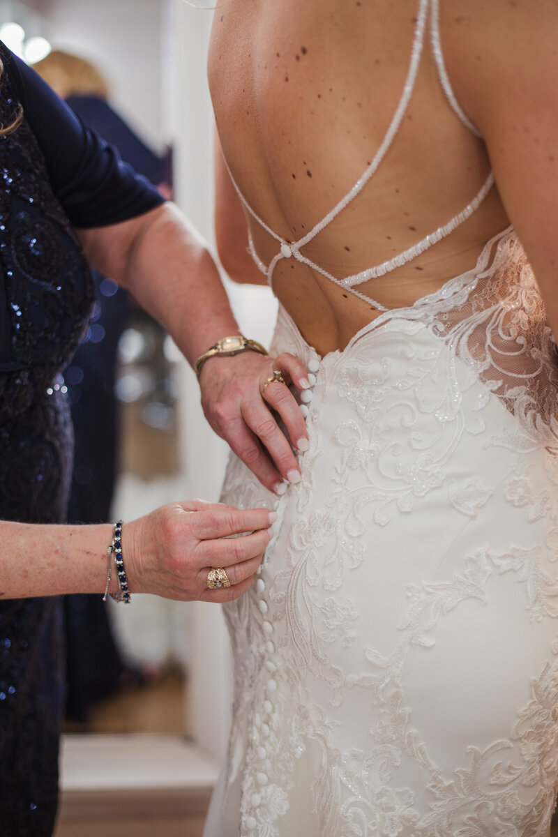 wedding dress being buttoned up by family