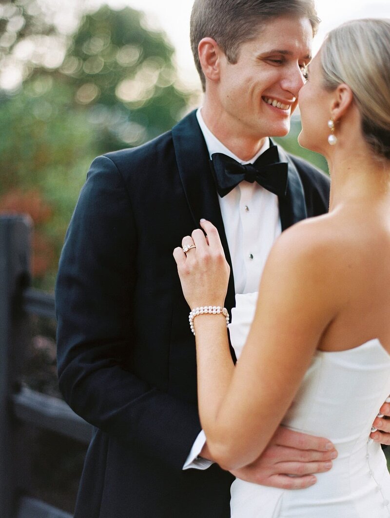 A bride and groom smile at one another while posing for film photographer in Asheville