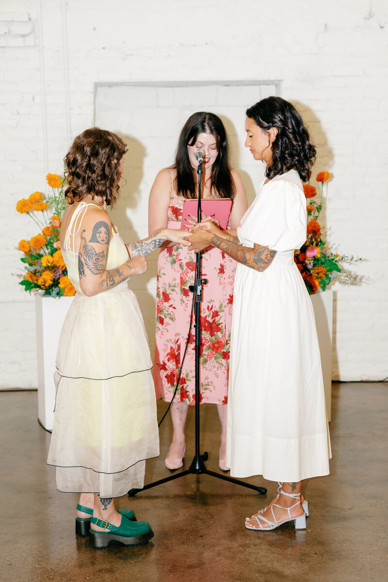 Officiant reads ceremony script while brides exchange rings