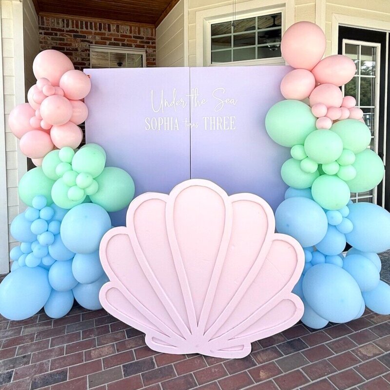 Mermaid and seashell themed birthday party with balloons, big pink shell, and custom purple backdrop in Fort Meyers