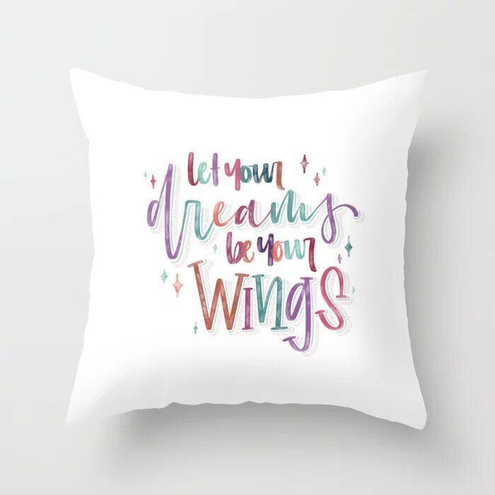 Custom hand lettered text "let your dreams be your wings" on a pillow
