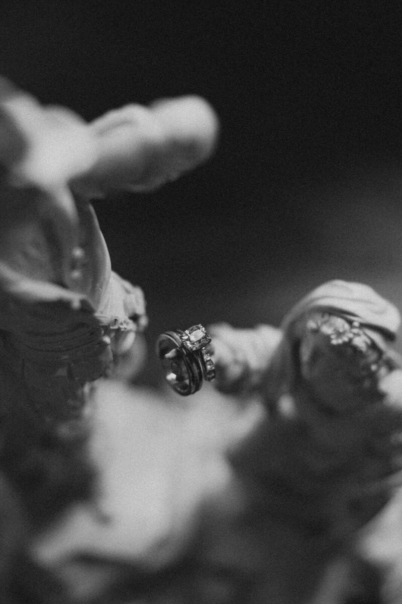 Wedding rings being held by a statue at chateau Domaine du Réveillon in Burgundy France, documented by Andrea-Marie Photography
