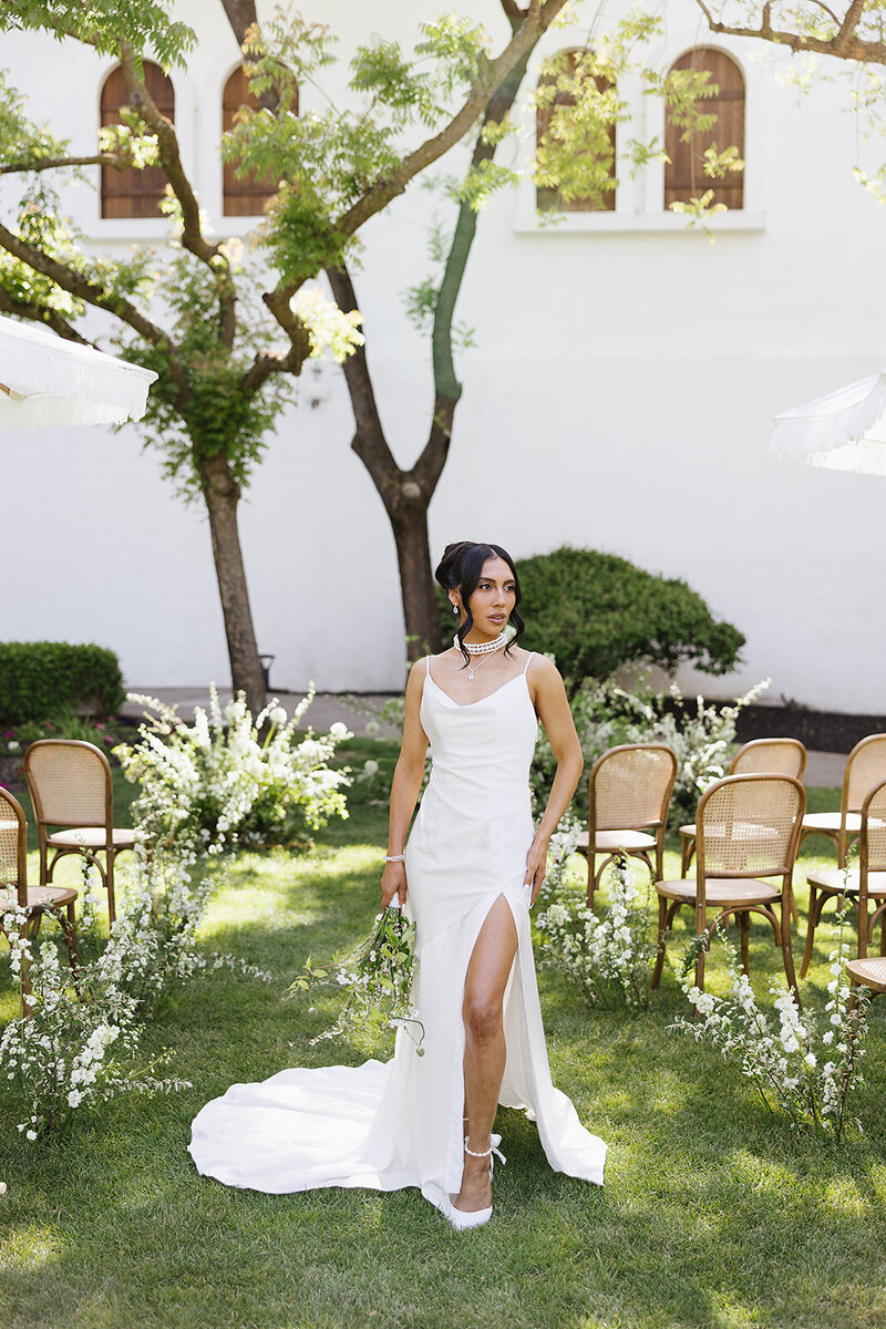 Bride in white cowel neck wedding dress standing in front of  the alter