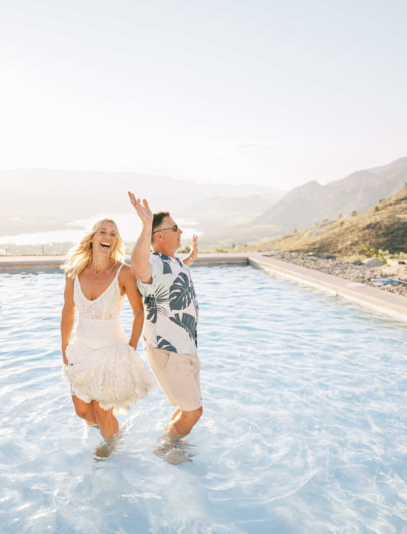 a couple dancing in a blue pool on top of a mountain during their wedding at golden hour