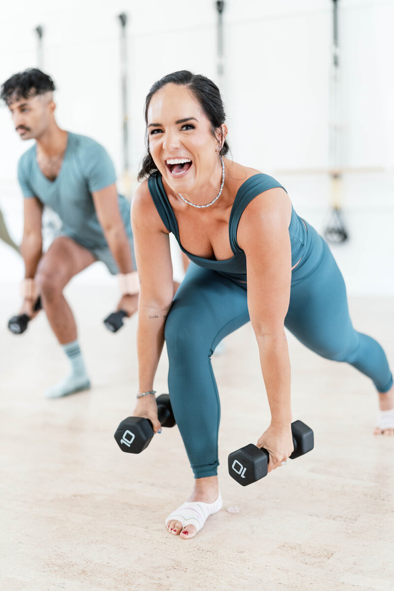 woman doing lunge with weights and laughing