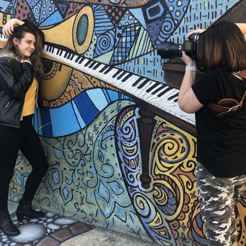 Photo shoot of senior girl leaning against graffiti wall