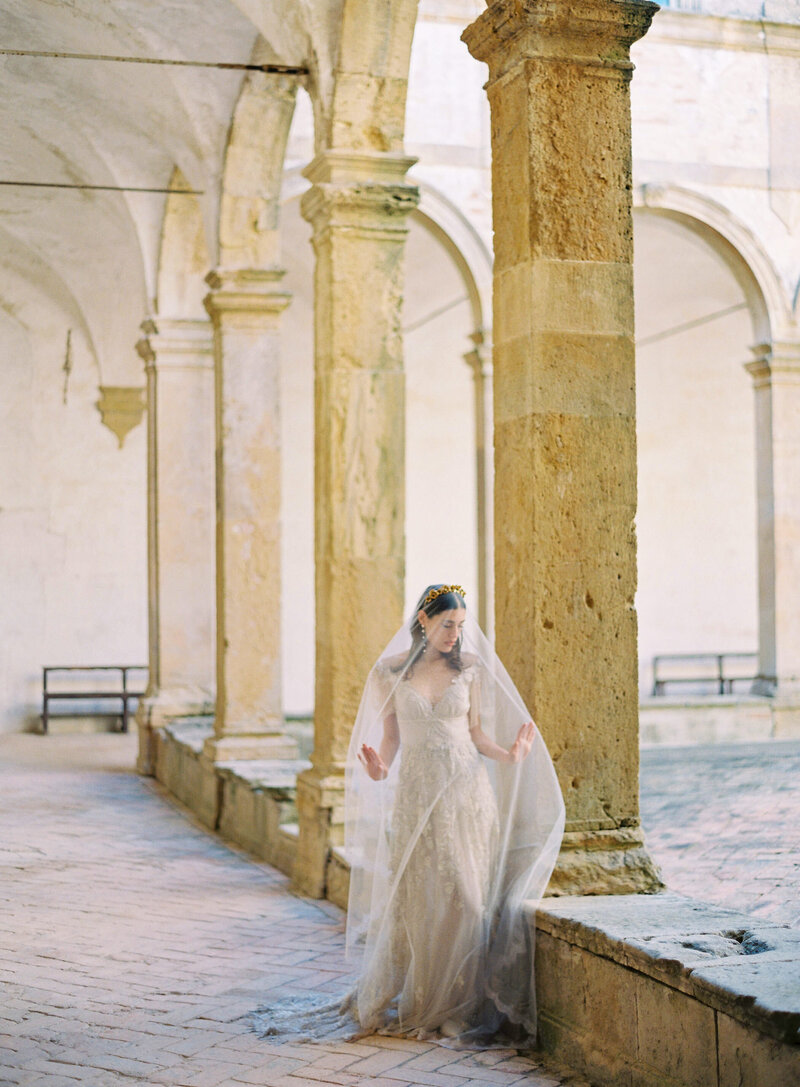 Female model in a wedding dress in front of a ancient stone pillar posing for a photography,