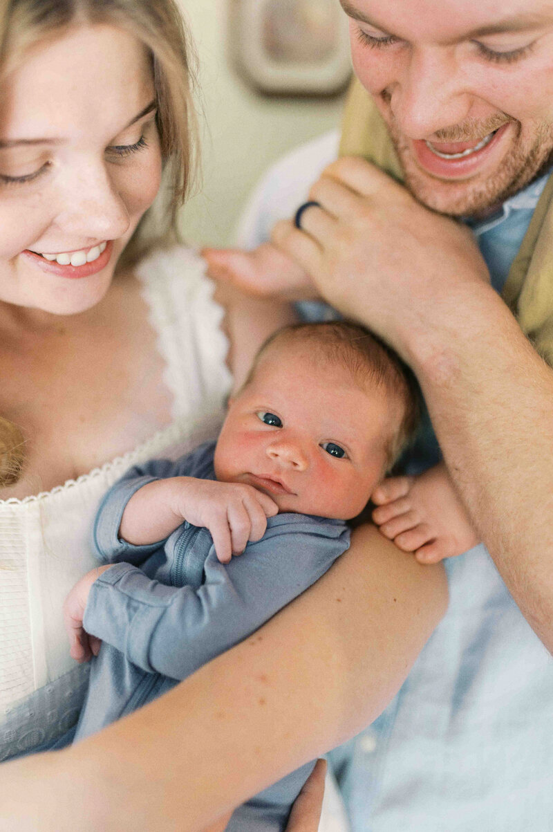 Family with toddler sitting on dad's shoulders with toes touching mom's arm while mom smiles down and holds newborn baby who looks at viewer  by Portland Family Photographer Emilie Phillipson Photography. 