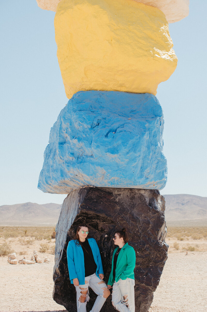 Two girls posing in front of a black rock.