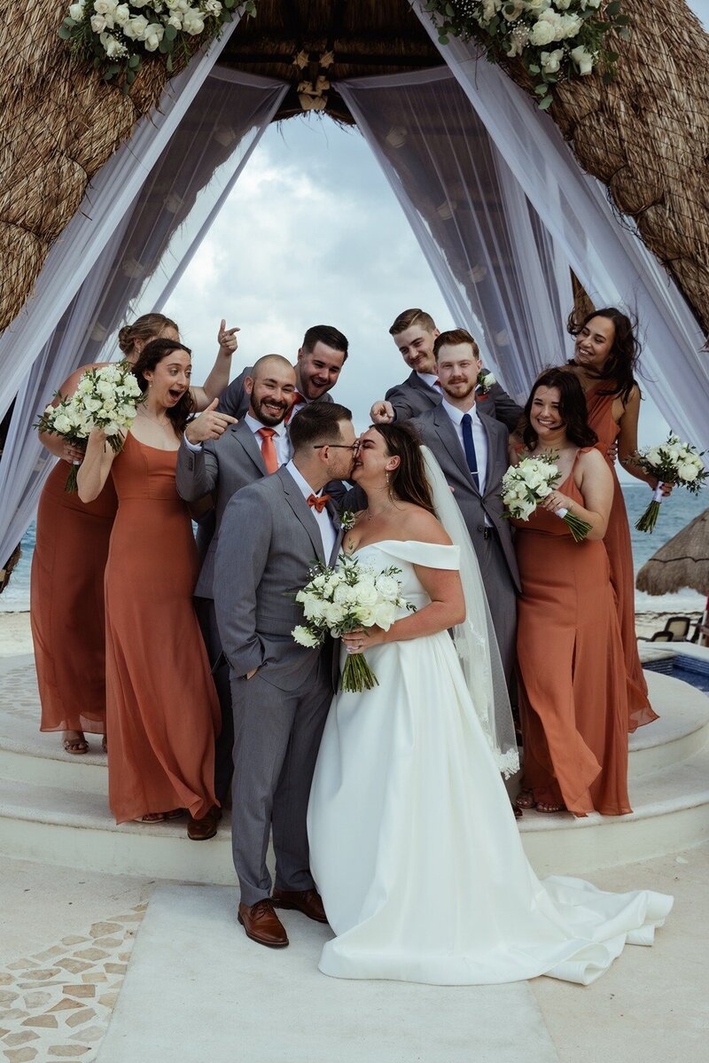 bride and groom sharing a kiss surrounded by their bridal party