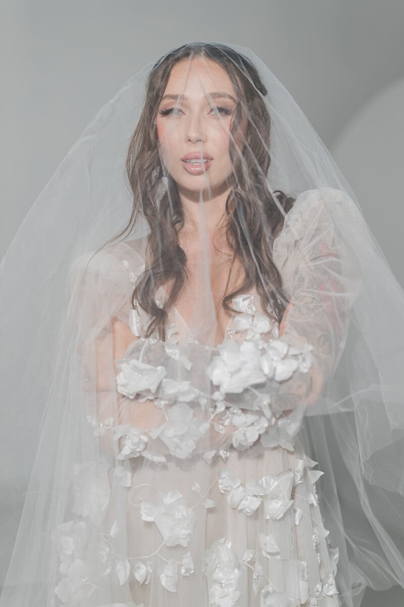 Portrait of a model in a wedding gown, with a veil covering her face, exuding timeless elegance.