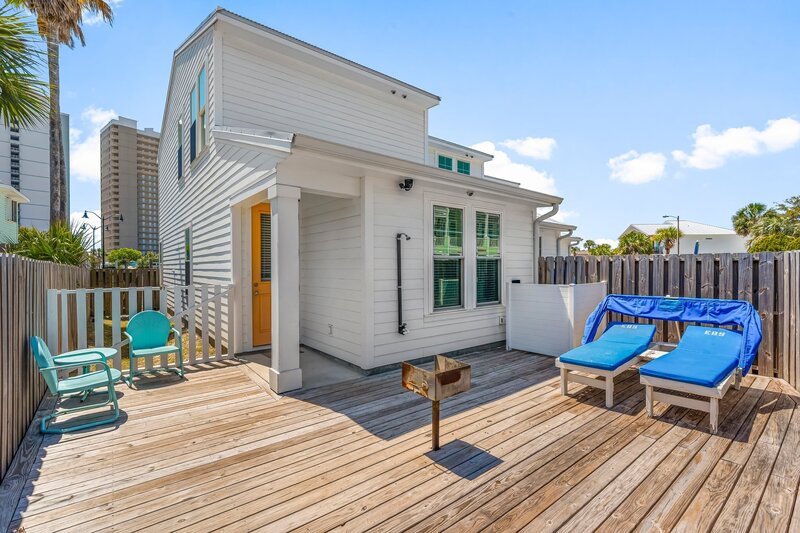 Private fenced-in deck with loungers, a charcoal grill, and a peek of the orange door entry at Welcome to Paradise, Panama City Beach.