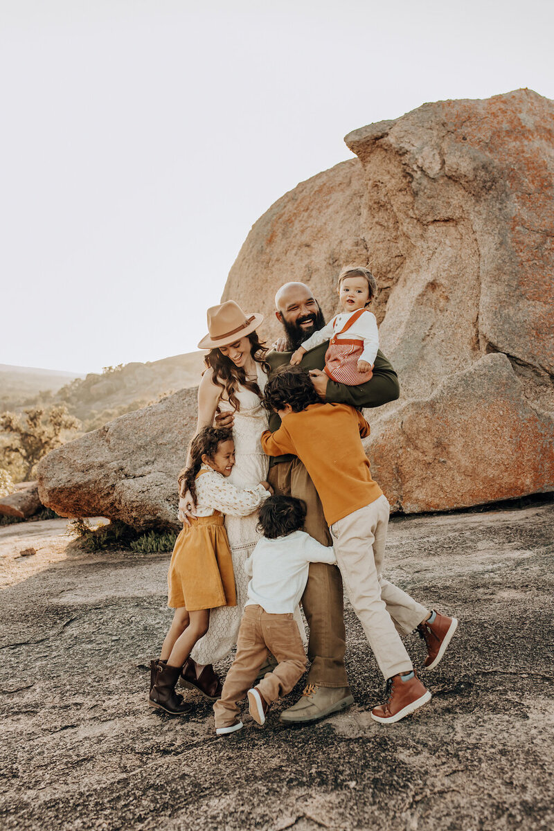 Hike enchanted rock photo session for a family of 6. They are playfully hugging each other for a fall photo session.