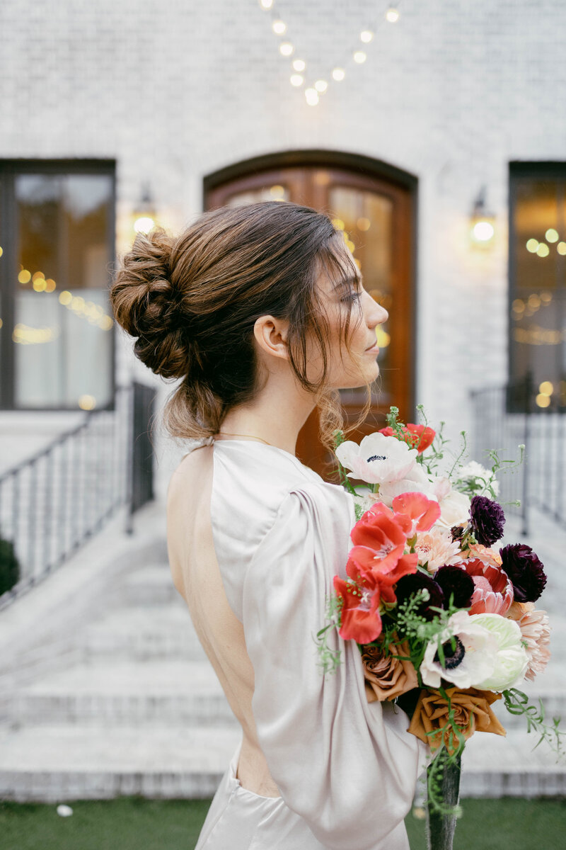 Bride in open-back dress posing with bouquet.