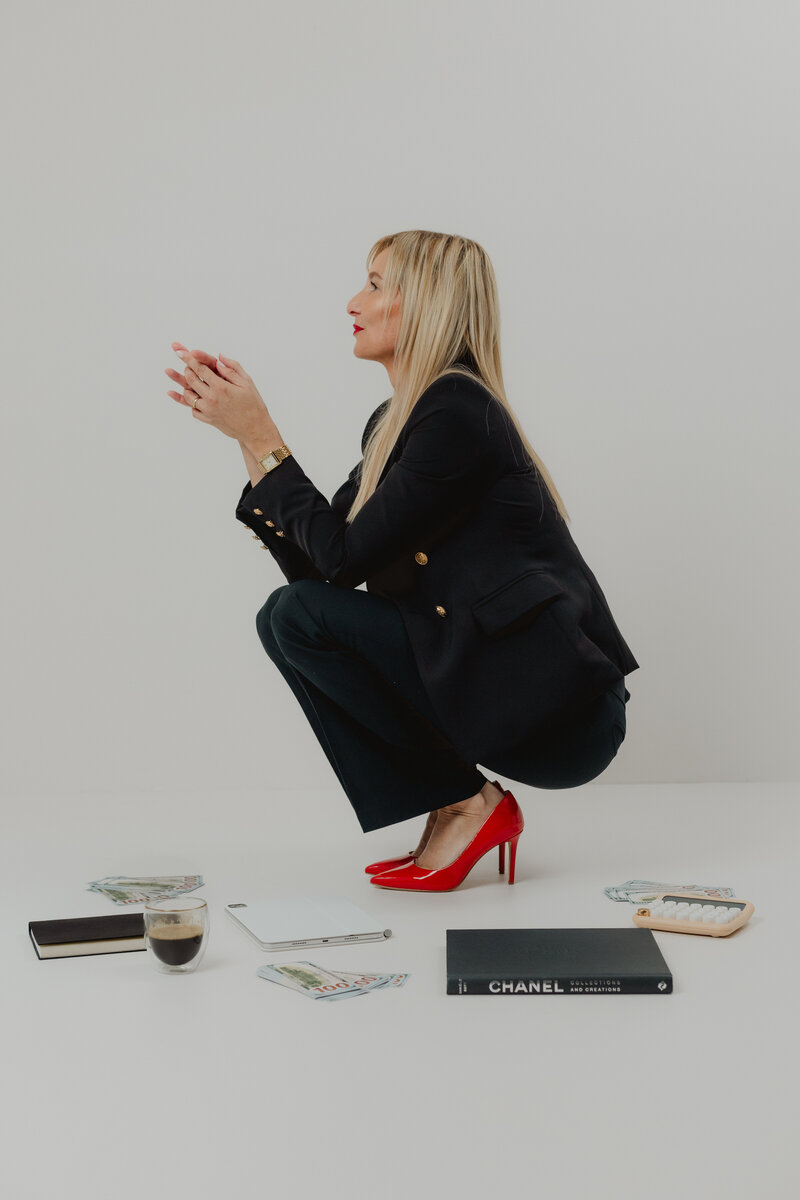 woman in luxury clothing and red heels surrounded by coffee and books
