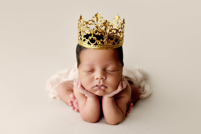 Newborn posing with a crown in a professional photography studio