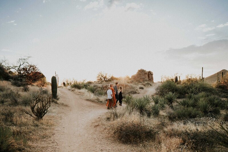 A family walks together down a dirt path while holding hands