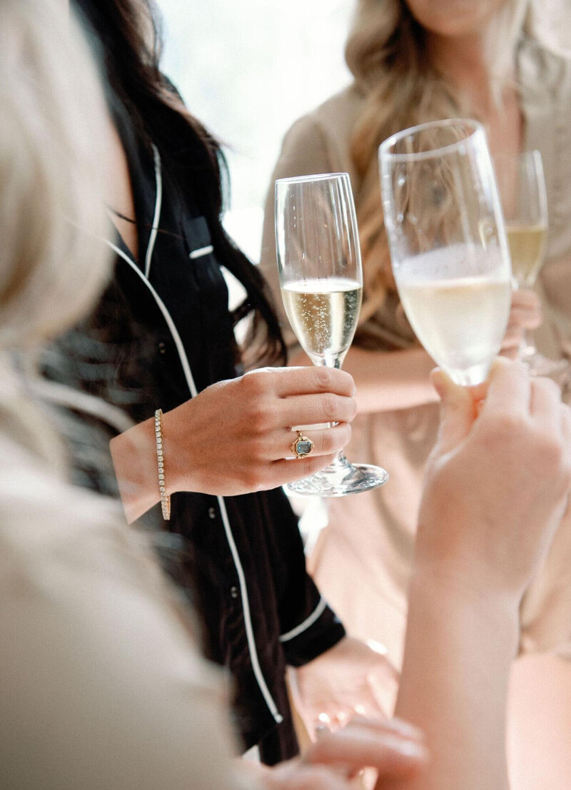 A bride and her wedding party hold champagne glasses in celebration
