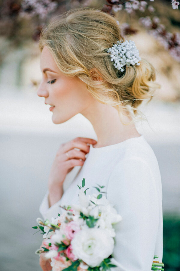 close up side view of a bride holding a bouquet and touching wedding dress collar