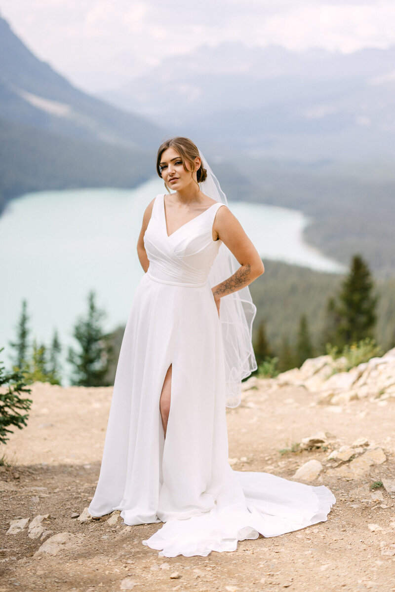 This elegant portrait captures a bride posing at Peyto Lake following her intimate and refined elopement in Banff National Park. The stunning turquoise waters and rugged landscape provide a breathtaking backdrop, highlighting her grace and the serene beauty of her wedding day.