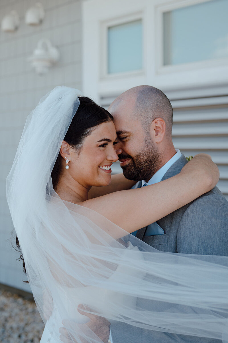 Wedding couple embracing with veil flowing in the wind 