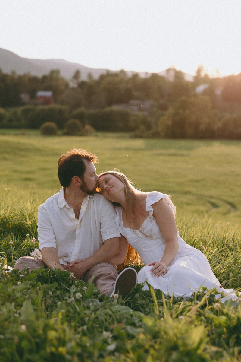 VT Wedding Photographer | Sincerely Liz Photography Documentary Wedding, Engagement, Elopement, Maternity and Newborn Photographer in New England | Couple sitting at a field while embracing for their engagement photos