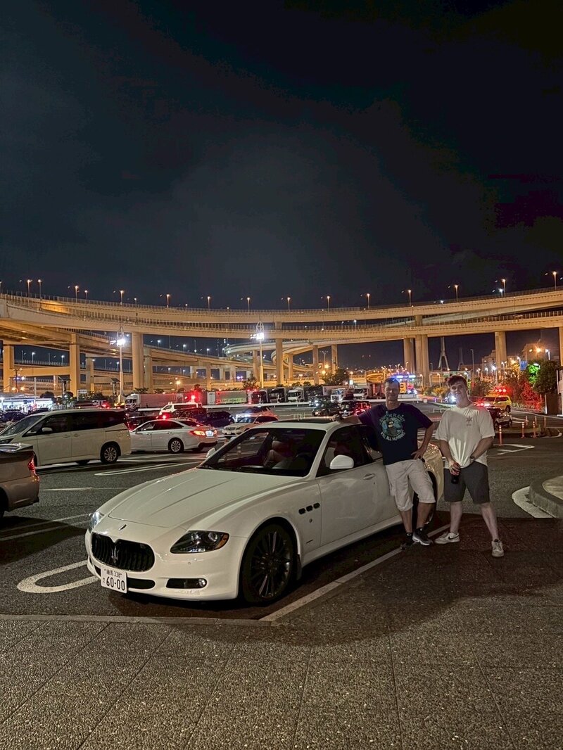 A couple embracing while enjoying a romantic night tour in Tokyo, with Tokyo Tower glowing in the background – experience curated by Tokyo Luxe Drive.