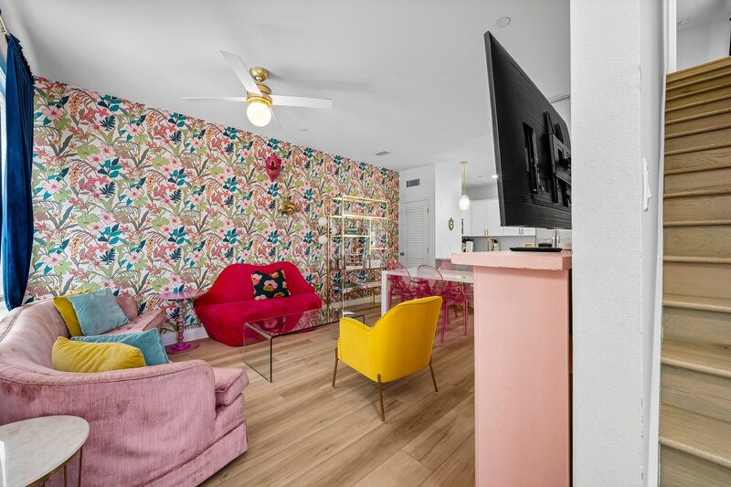 Playful and bold living room featuring floral wallpaper, velvet seating, and a smart TV—perfect for Instagram-worthy moments near 30A and Carillon Beach.