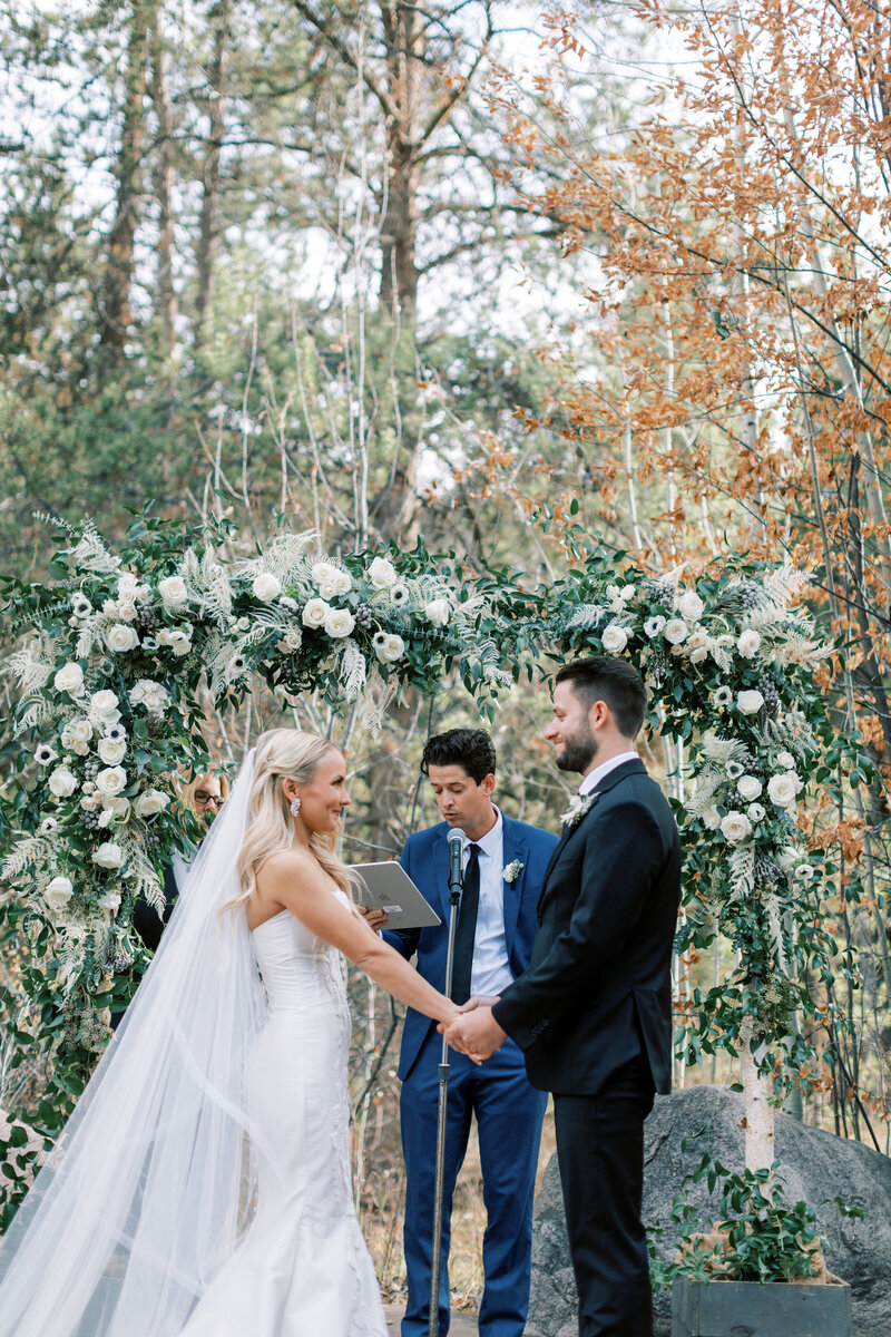 Portrait of bride and groom during their ceremony in Vail Colorado at Donovan Pavilion under a beautiful floral wedding arch.