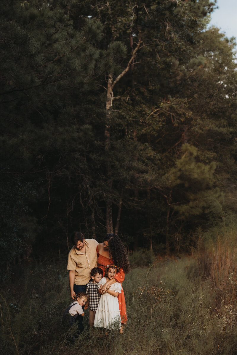 Family of five hugging together during an outdoor photo session in The Woodlands, Texas
