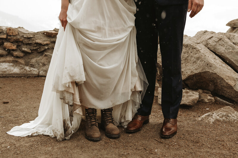 bride and groom standing outside while wearing hiking boots