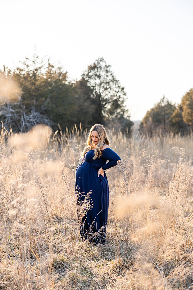 Soft, timeless maternity image of mom-to-be standing in a meadow during sunset.