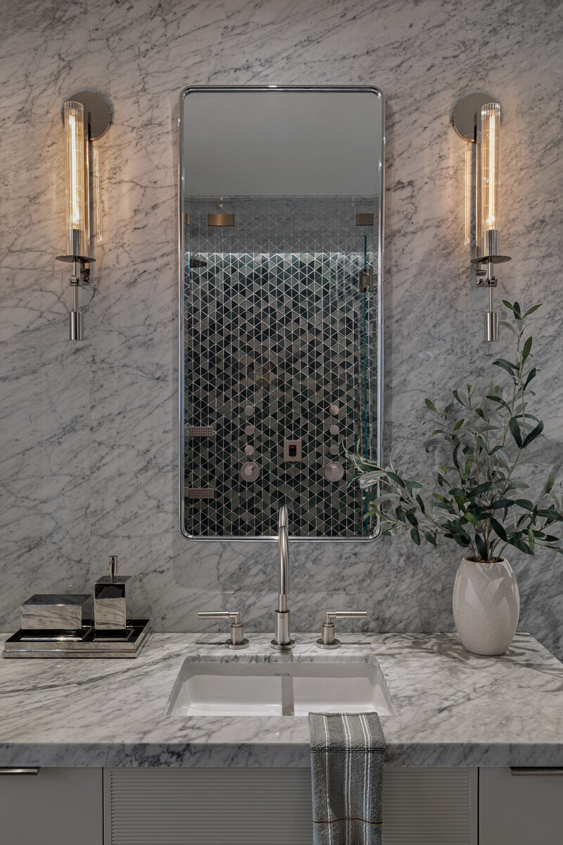 Close up shot of custom white vanity, stone-clad walls and custom mirrors and lighting by Sister Studio.