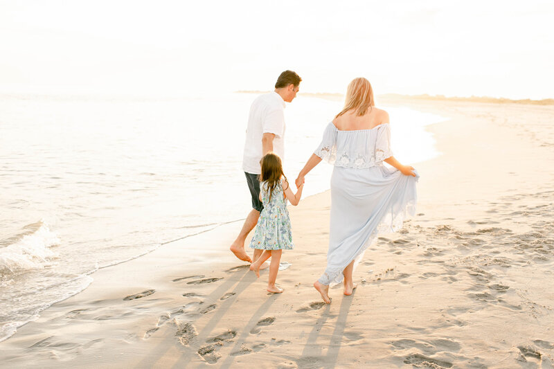 family with daughter walking on beach holding hands by new jersey family photographer 