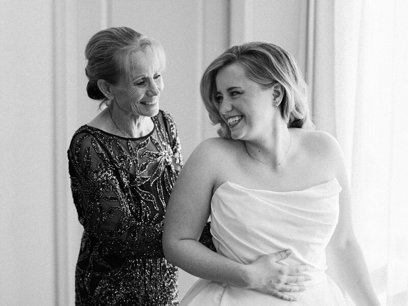 The bride and mother of the bride share an intimate moment while getting the bride into her wedding dress