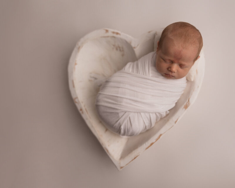 baby sleeping in a heart bowl