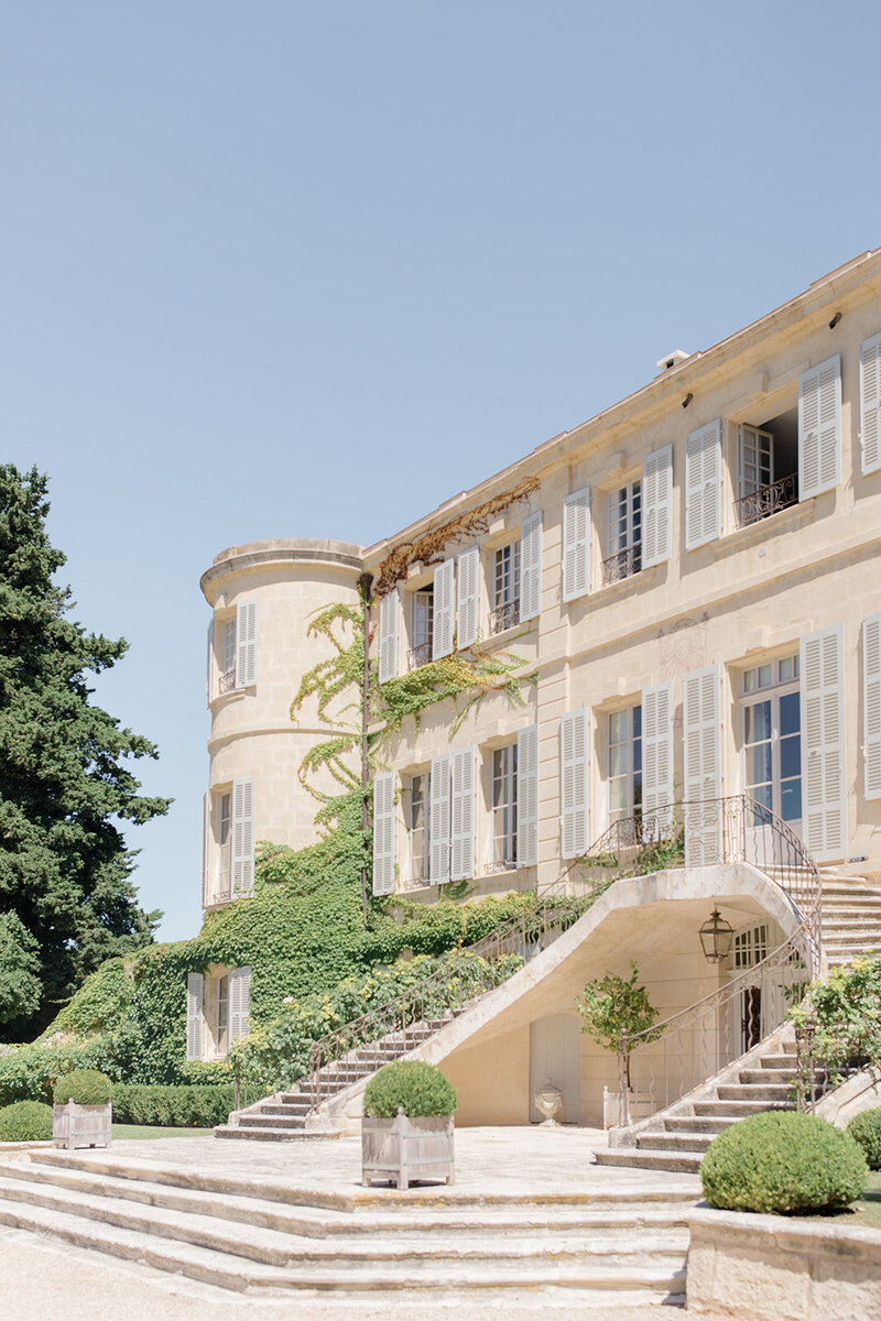 A historic chateau with a sweeping entry staircase and blue shutters for a luxury multi-day destination wedding