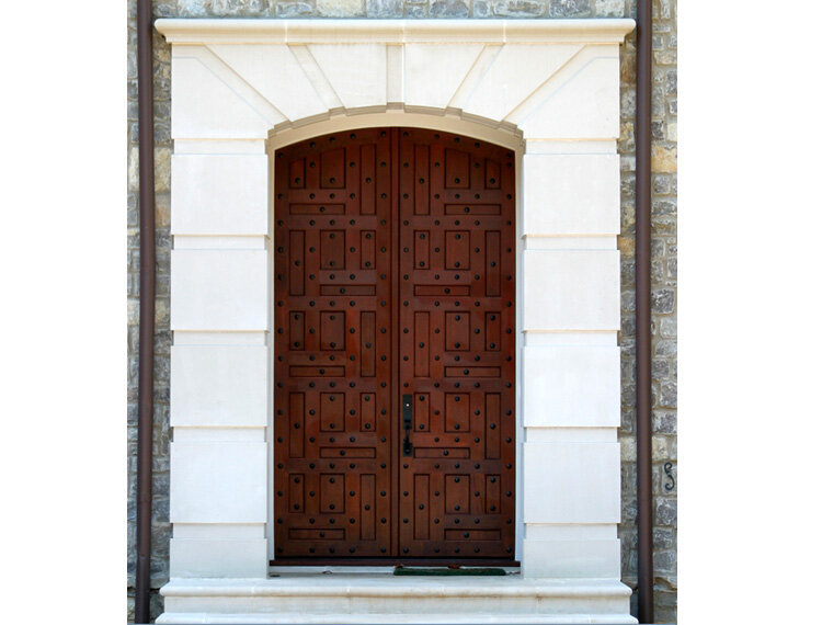 Architectural door surround made of cast stone with heavy wooden doors